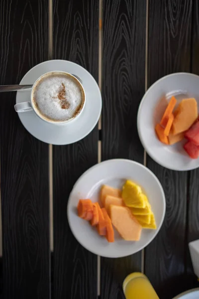 Deliciosa xícara de latte e frutas fatiadas para o café da manhã na mesa preta — Fotografia de Stock