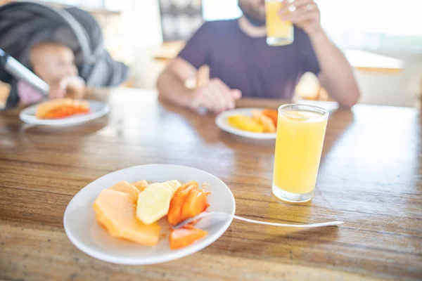 Deliciosas rebanadas de fruta y zumo de naranja sobre una mesa de madera con fondo borroso — Foto de Stock