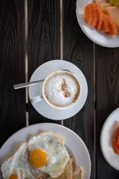 Deliciosa xícara de café latte e ovos fritos para o café da manhã na mesa preta — Fotografia de Stock