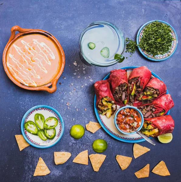 Deliciosos burritos e condimentos mexicanos na superfície escura Fotografia De Stock