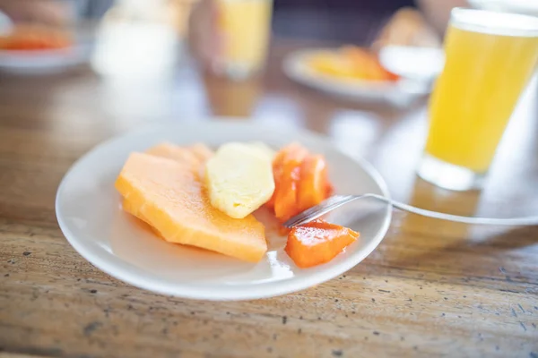 Deliciosas fatias de frutas e suco de laranja na mesa de madeira com fundo embaçado Imagem De Stock