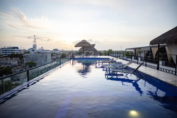 Vista surpreendente da piscina e camas de praia no telhado com pôr do sol como fundo Imagens Royalty-Free