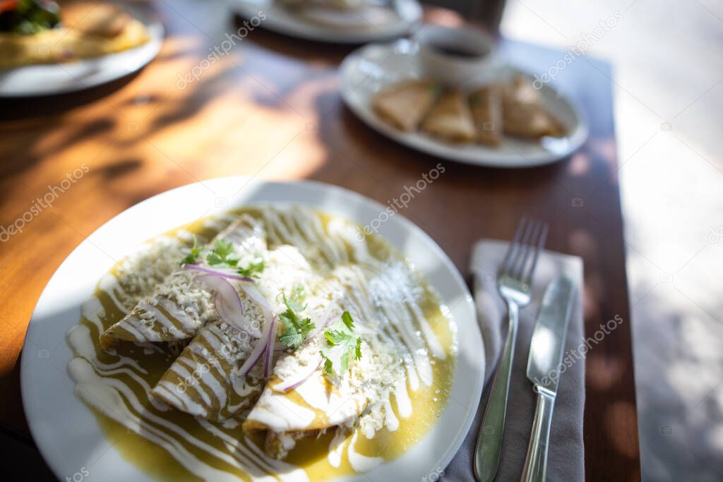 Sunlight on plate with delicious green Mexican enchiladas