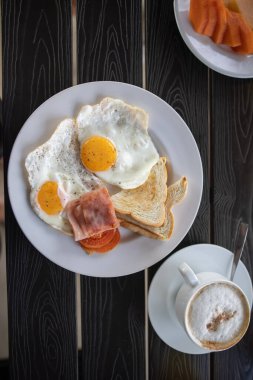 Yağda yumurta ve siyah masada bir fincan kahve ile nefis bir kahvaltı.