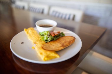 Lezzetli omlet, sebze, tost ve kahverengi masanın üstünde fasulye.