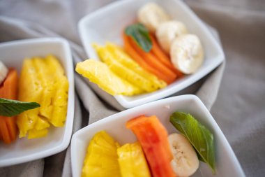 Kırışık gri peçetede taze meyve dilimleri olan kare tabaklar.