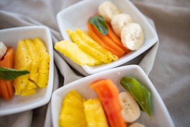 Kırışık gri peçetede taze meyve dilimleri olan kare tabaklar.