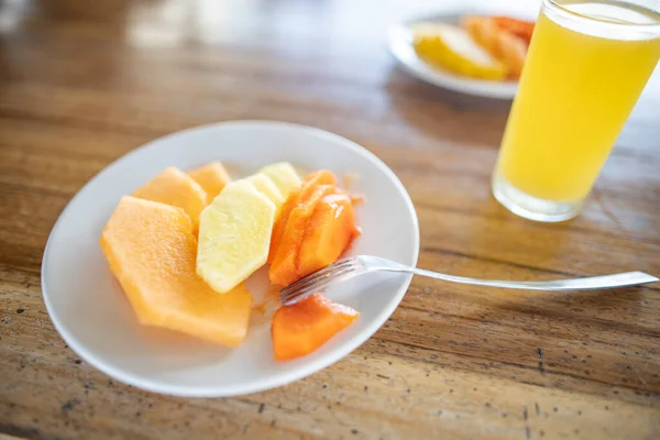 Lezzetli meyve dilimleri ve portakal suyu ahşap masada bulanık arka planda.
