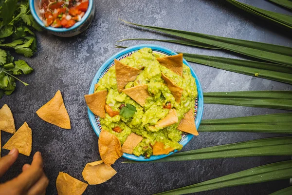Schaal van heerlijke guacamole met tortilla chips op donker oppervlak — Stockfoto