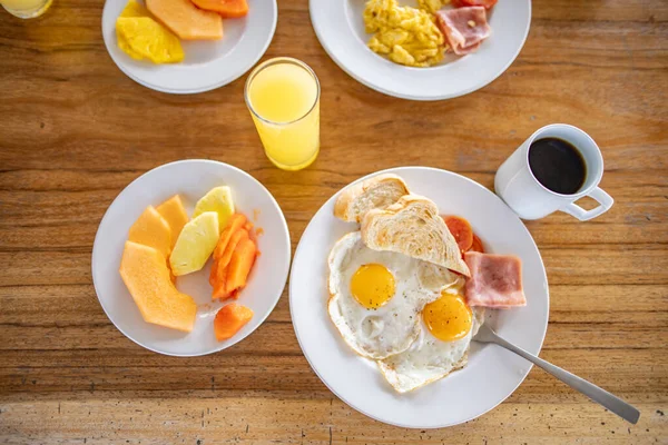 Läckra stekta ägg, frukt, apelsinjuice och en kopp kaffe på träbord — Stockfoto