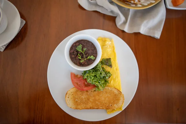 Talíř s chutnou omeletou, zeleninou, tousty a fazolemi na hnědém stole — Stock fotografie
