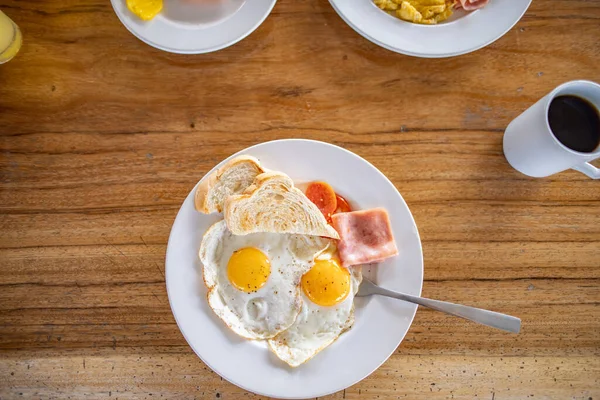 Läcker frukost med stekta ägg och en kopp kaffe på träbord — Stockfoto