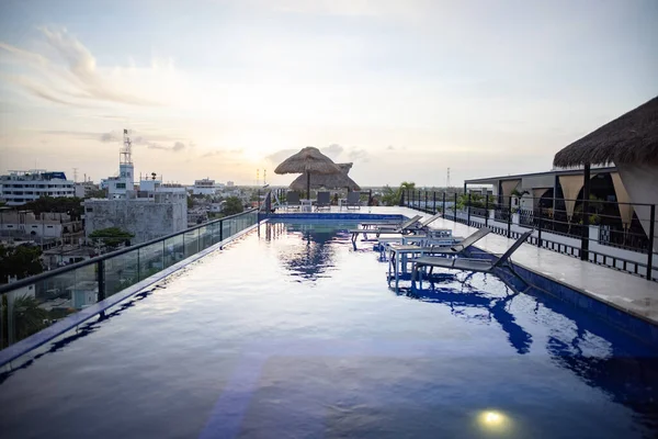 Bela vista da piscina e camas de praia no telhado com pôr do sol como fundo Imagem De Stock