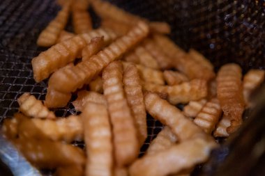 Kızartma sepetinde birkaç dalgalı patates kızartması yakın plan.