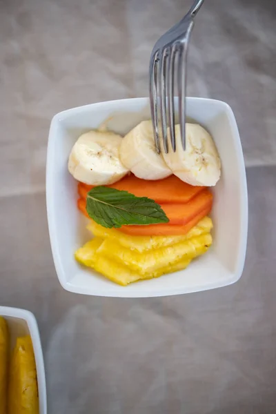 Silver gaffel peta skivad frukt på fyrkantig vit platta — Stockfoto