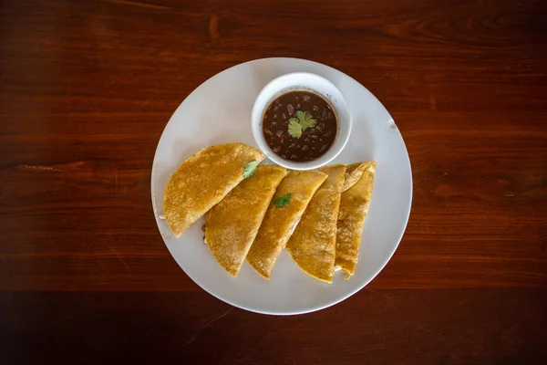 Placa con quesadillas tradicionales y taza de frijoles sobre mesa marrón — Foto de Stock