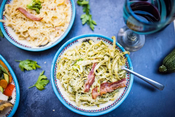 Deux assiettes de délicieuses pâtes avec des lanières de bacon au-dessus de la surface sombre — Photo