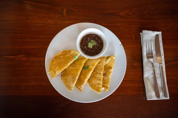 Talíř s tradičními quesadillami a šálkem fazolí na hnědém stole — Stock fotografie