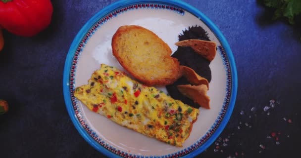 Piring dengan telur dadar lezat, roti panggang, dan kacang goreng di permukaan hitam — Stok Video