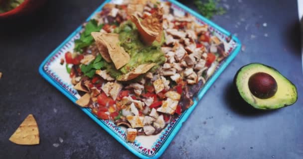 Délicieuse viande hachée au guacamole sur surface noire entourée de condiments — Video