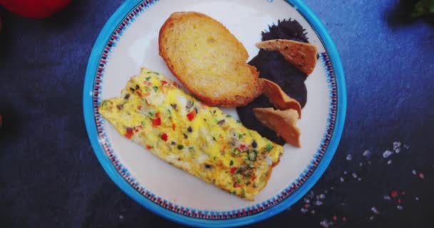 Prato com deliciosa omelete, torrada e feijão refrito na superfície preta — Vídeo de Stock