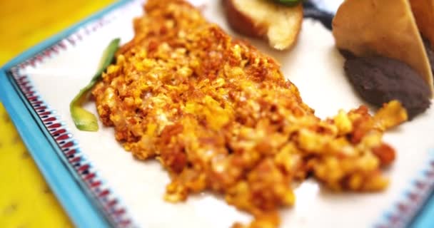 Tallrik med kryddiga äggröra och tortillachips på gul yta — Stockvideo