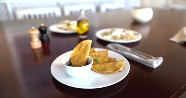 Tallrik med traditionella quesadillas och kopp svarta bönor på brunt bord — Stockvideo