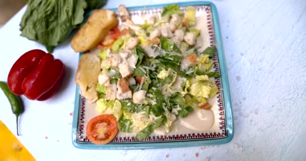 Placa de deliciosa ensalada rodeada de verduras en la superficie blanca — Vídeos de Stock