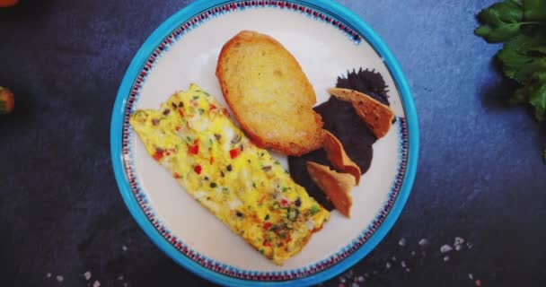Piring dengan telur dadar lezat, roti panggang, dan kacang goreng di permukaan hitam — Stok Video