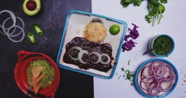 Heerlijke mol, rijst, uienschijfjes en meer voedsel op tweekleurig oppervlak — Stockvideo