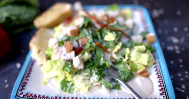 Placa de deliciosa ensalada rodeada de verduras y sal en la superficie negra — Vídeos de Stock