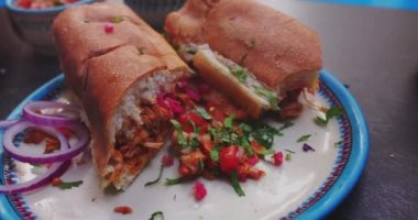 Beyaz tabakta pico de gallo ile nefis sandviçler.