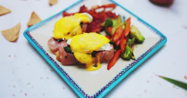 Piatto di deliziose uova benedetto e verdure arrosto sulla superficie bianca — Video Stock