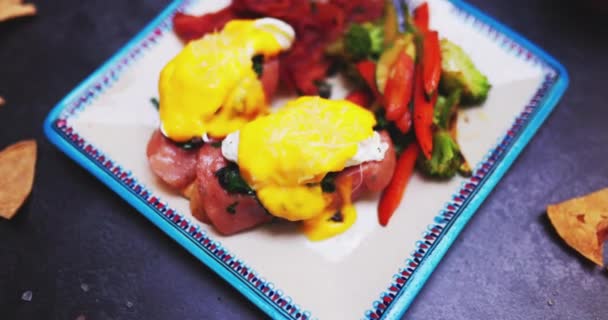 Placa de deliciosos huevos benedicto y verduras asadas en la superficie negra — Vídeos de Stock