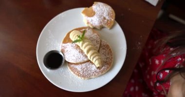 Bir tabak lezzetli krep, krema ve kahverengi masada dilimlenmiş muz.