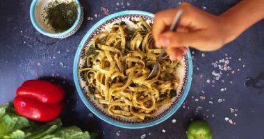 Elleri çatallı lezzetli erişteleri siyah yüzey üzerinde büküyor.