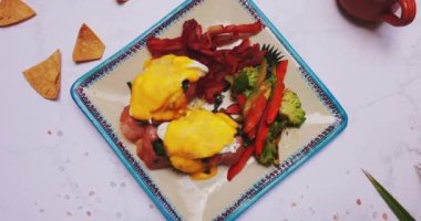 Lezzetli yumurta tabağı Benedict ve kızarmış sebzeler beyaz yüzeyde