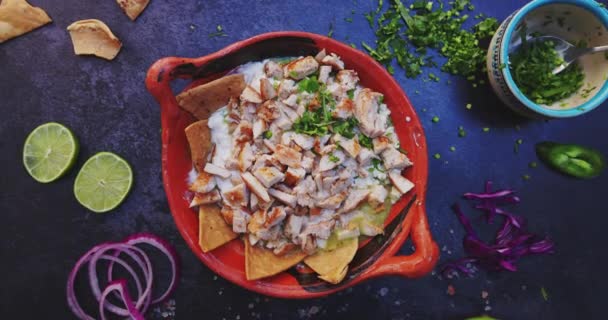 Lerskål med läckra chilaquiles och hackat kött omgiven av mer mat — Stockvideo