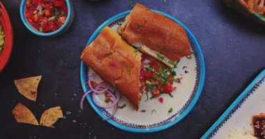 Lezzetli sandviçler, pico de gallo ve siyah yüzeyde daha fazla yiyecek.