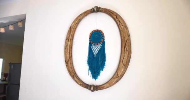 Beautiful blue dreamcatcher hanging from wooden frame on white wall — Stock Video
