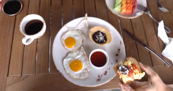 Mão feminina segurando torrada com ovos mexidos e feijão frito acima do prato — Vídeo de Stock