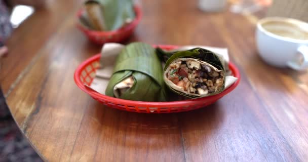 Tasty burritos wrapped with banana leaf on wooden table — Stock Video
