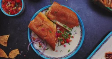 Lezzetli sandviçler, pico de gallo ve siyah yüzeyde daha fazla yiyecek.