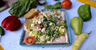 Beyaz yüzeyde sebzelerle çevrili lezzetli salata tabağı.