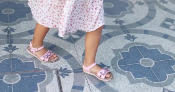 Niños pies en sandalias lindas felizmente patadas y saltando en el suelo de azulejos azules — Vídeo de stock