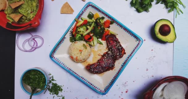 Deliciosa carne asada, arroz, verduras y más alimentos en la superficie blanca — Vídeos de Stock