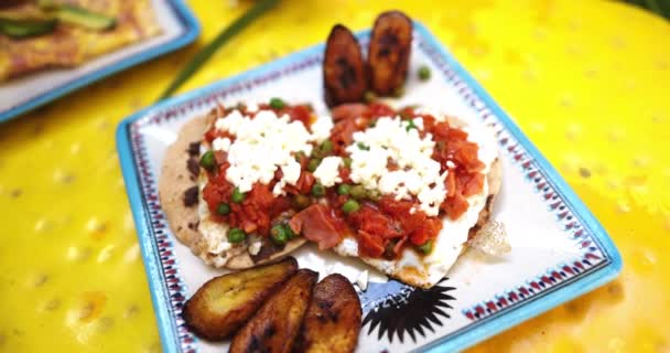 Teller mit Huevos Rancheros und gebratenen Bananenscheiben auf gelber Oberfläche — Stockvideo