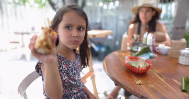 Cute little girl at wooden table showing half-eaten burrito — Stock Video