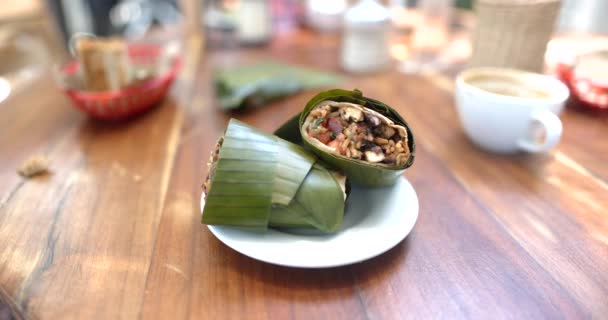 Burritos saborosos embrulhados com folha de banana na mesa de madeira — Vídeo de Stock