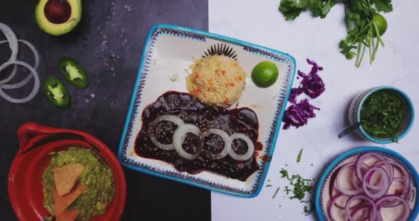 Heerlijke mol, rijst, uienschijfjes en meer voedsel op tweekleurig oppervlak — Stockvideo